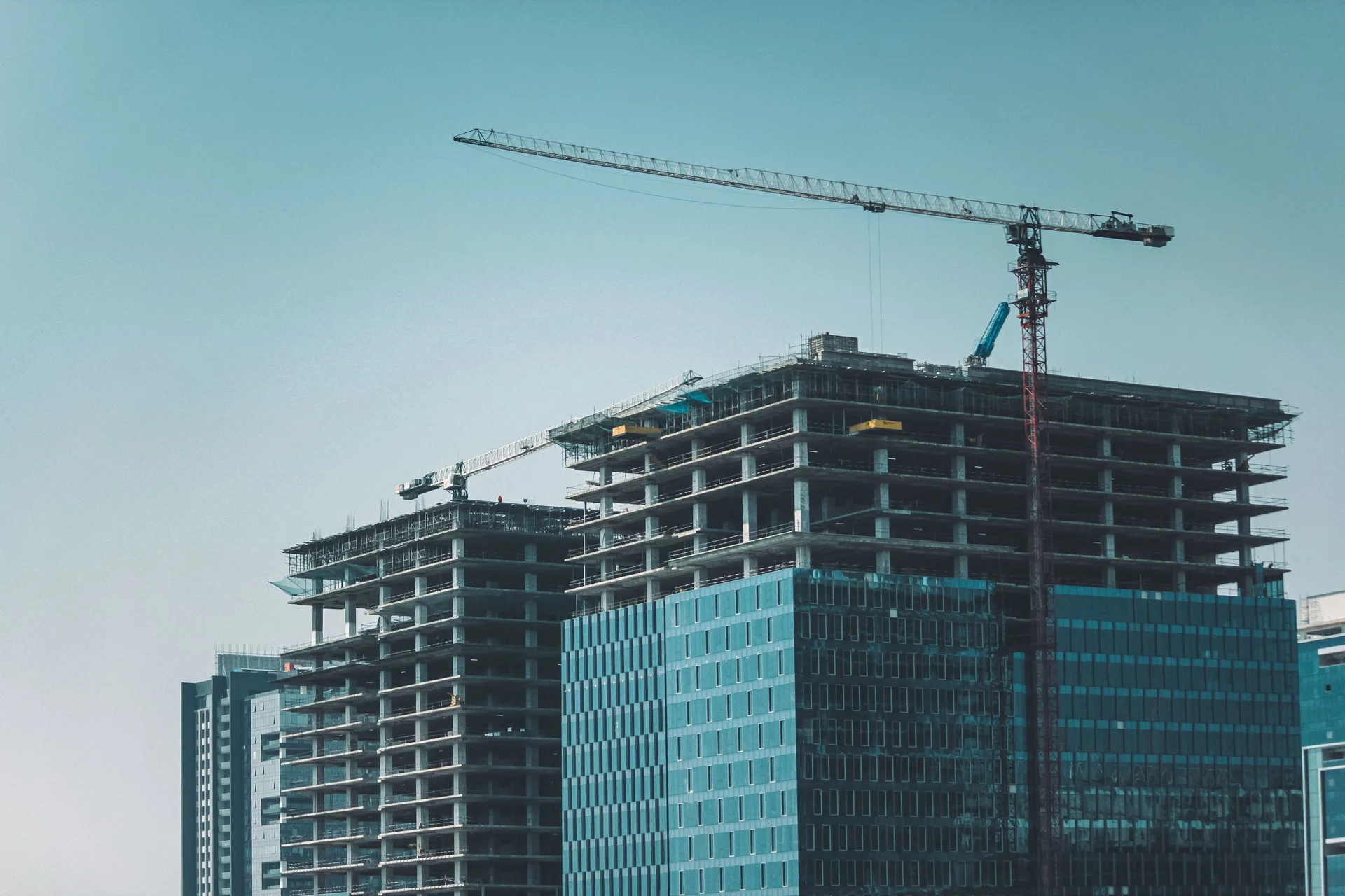 Cranes and a building under construction against the sky.